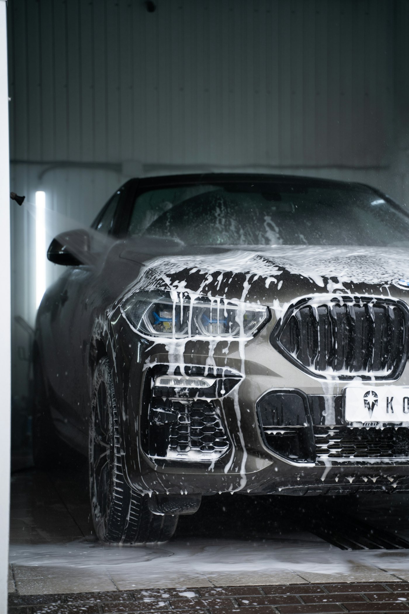 Placeholder stock photo: grey car covered in soap suds mid-wash